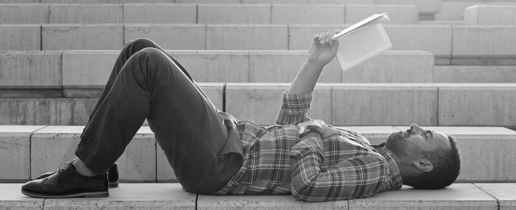 Black and White photo of a Man reading on the steps