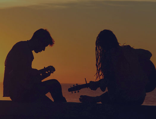 Guys playing guitar together at beach