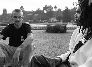 black and white image of two men sitting, talking in a park