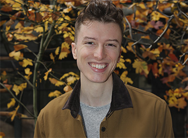 a young lad flashing a brilliant smile in front of the cool color tones of autumn