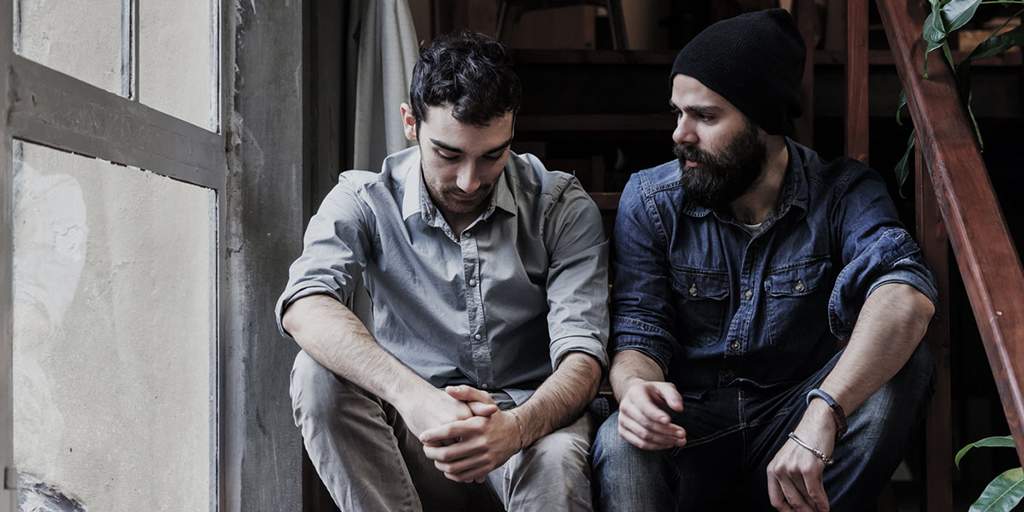 Couple of young men talking on the stairs of an office