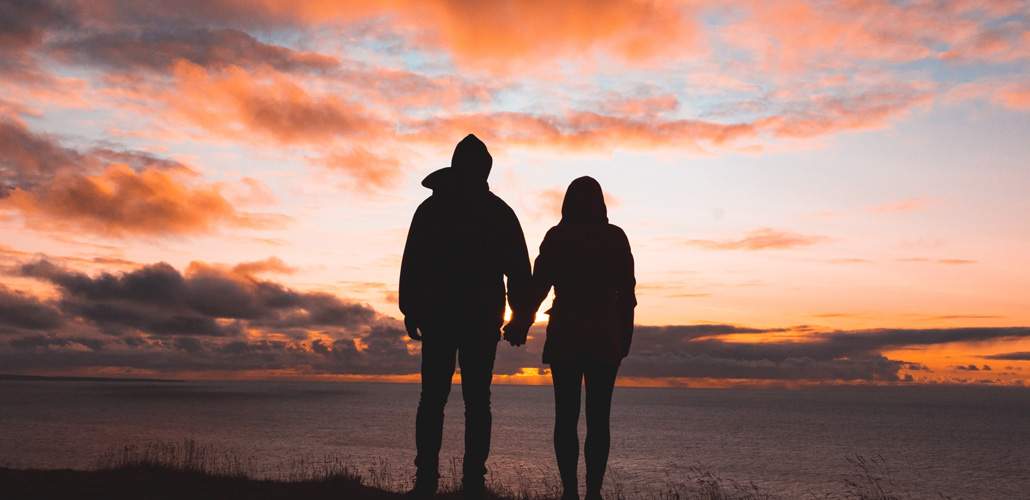 Couple holding hands and watching sunset