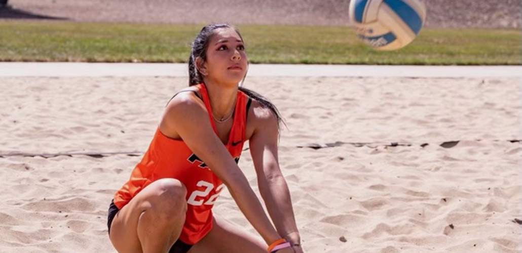 Photo of Hania crouched on beach preparing to hit volleyball