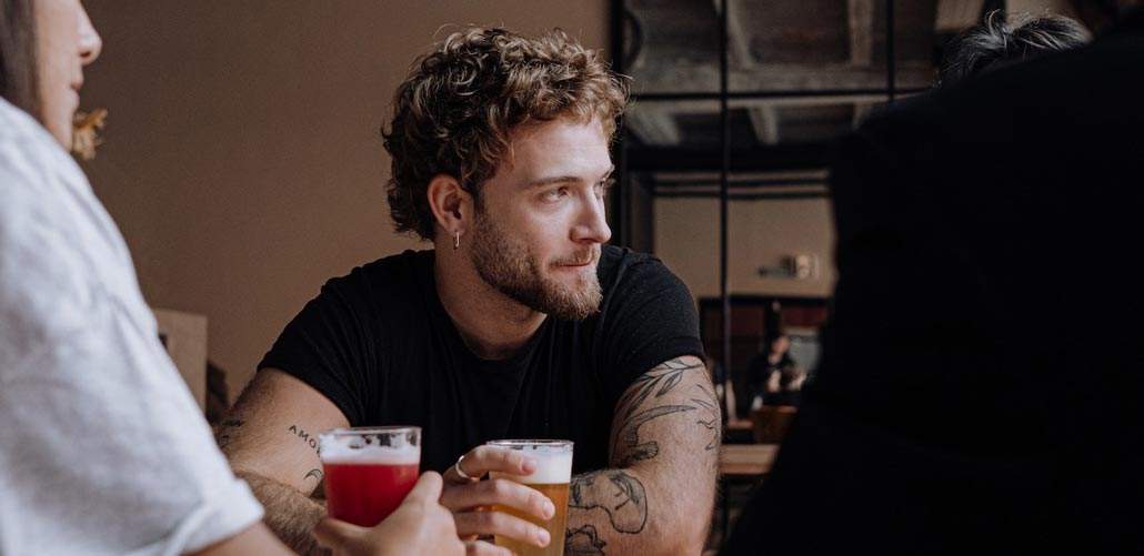 Man having beers with friends looks off to side