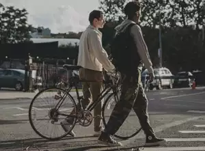 Two young men walking beside a bicycle