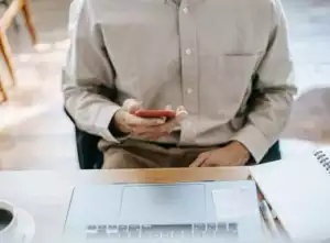 Man looking at phone while writing