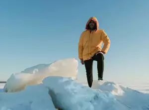 Person Wearing Orange Puffer Jacket Standing on Snow Covered Ground